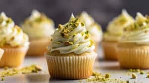 Luscious Pistachio Cupcakes with Vanilla Buttercream Frosting on a white cake stand.