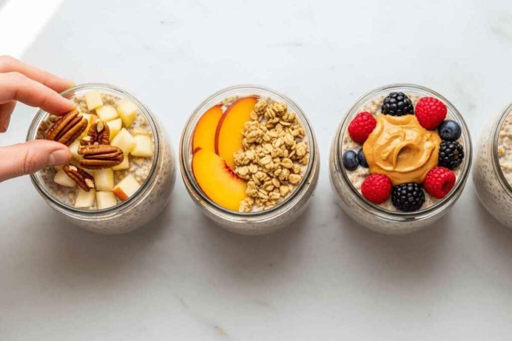 Four jars of overnight oats recipe topped with apples and pecans, peaches and granola, and berries with peanut butter