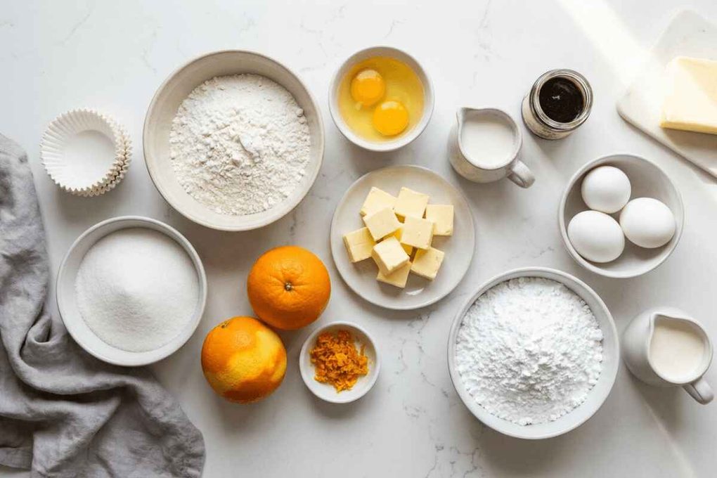 Ingredients for Orange Creamsicle Cupcakes with oranges, flour, eggs, butter, and sugar